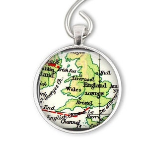 May include: A silver ornament featuring a map of the British Isles. The map is in a circular glass cabochon and shows the countries of England, Wales, and Scotland. The ornament is perfect for a Christmas tree or any other holiday decor.