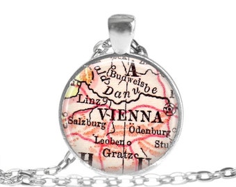 Könnte beinhalten: Eine silberne Halskette mit einem runden Glasanhänger, der eine Vintage-Karte von Österreich mit der hervorgehobenen Stadt Wien zeigt. Die Karte ist in Rosa-, Braun- und Weißtönen gehalten.