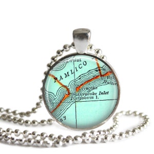 May include: A silver necklace with a round pendant featuring a vintage map of the Pamlico Sound in North Carolina. The map is printed on a light blue background with orange lines and text.