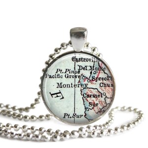 May include: A silver necklace with a round pendant featuring a vintage map of the Monterey, California area. The map shows the towns of Castroville, Del Monte, Pacific Grove, Spreckels, Monterey, Carmel, and Pt. Sur.