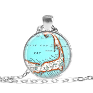 May include: A silver necklace with a round glass pendant featuring a vintage map of Cape Cod Bay. The map is in shades of blue, orange, and brown, with the names of towns and landmarks printed on it.