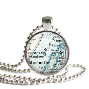 May include: Silver-toned pendant necklace featuring a round charm with a vintage map design. The map shows the area of Marinette, with blue highlighting the water features. The necklace has a ball chain.