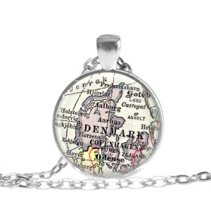 May include: A silver-toned pendant necklace featuring a circular charm with a vintage map of Denmark. The map includes cities like Copenhagen and Aarhus, with a silver chain. The pendant is round and has a glass-like finish.