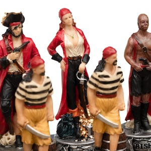 May include: A collection of pirate figurines. The figures are dressed in red coats, striped shirts, and bandanas. Some hold swords and pistols. The figurines are on a decorative base with a treasure chest and skull.