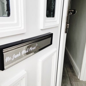 May include: White front door with a black and silver letterbox. The letterbox has a sticker that says "No Junk Mail Please" with a heart.