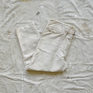 May include: A pair of light beige twill pants with a single front pocket and a belt loop. The pants are folded in half and laid flat on a white canvas background.