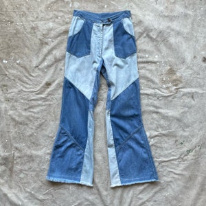May include: A pair of blue denim bell bottom pants with a patchwork design. The pants have a high waist and are made of a light-weight denim fabric.