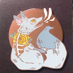 May include: A blue and white enamel pin of a fox with a skeletal ribcage and flowers. The fox is howling and has a copper background. The pin is numbered 3/100. Joyce Hwang, joycehwang.com, IG: @juicette