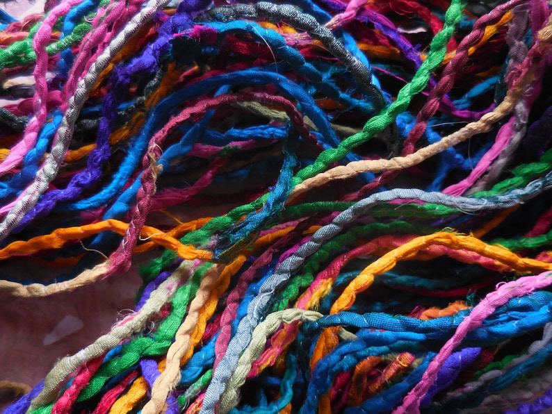 May include: A collection of colorful, twisted silk threads in various shades of blue, green, orange, pink, purple, and brown.