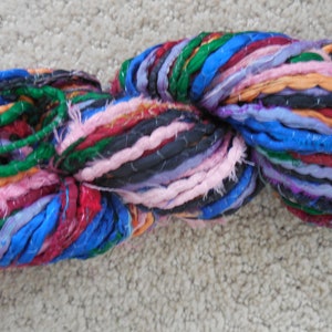 May include: A skein of colorful yarn made from recycled fabric scraps. The yarn is a mix of blue, green, pink, purple, red, and orange.