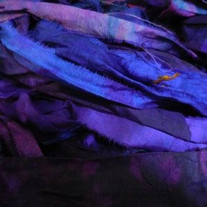 May include: A pile of purple and blue silk ribbon scraps. The ribbon is frayed and has a textured look.