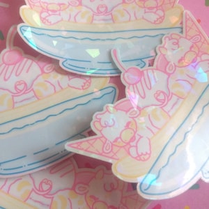 May include: A set of four stickers featuring cute cartoon animals enjoying a banana split. The stickers are holographic and have a rainbow iridescent finish.