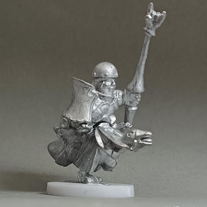 Può includere: Figurina in miniatura color argento di un guerriero a cavallo di una creatura. Il guerriero indossa un elmo e tiene in mano un bastone con un gesto della mano. La figurina è montata su una base bianca.