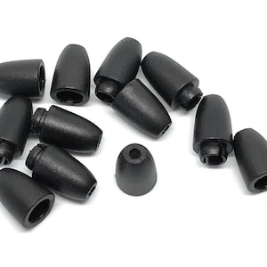 May include: A collection of black cord end caps, also known as cord locks, displayed against a white background. These small, cone-shaped plastic pieces have a hollow interior and are designed to secure cords.