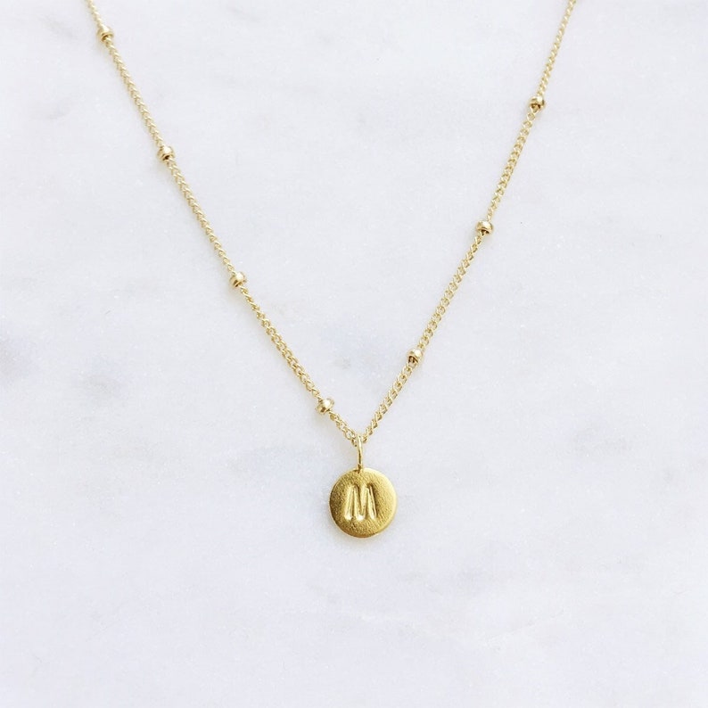 A dainty gold personalised, round letter pendant on a gold filled satellite chain