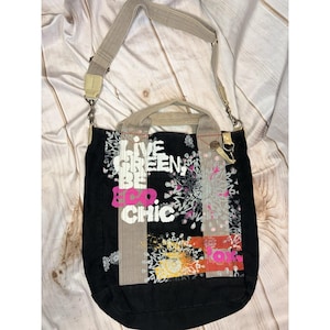 May include: Black tote bag with a shoulder strap and top handles. The bag features the text "LIVE GREEN BE ECO CHIC" in white and pink. The design includes floral and geometric patterns in various colors.