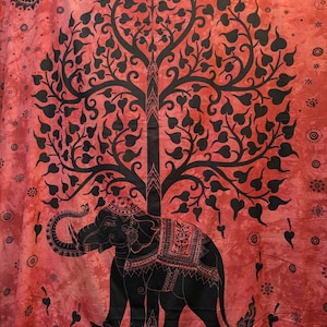 May include: Red and black tapestry featuring a detailed elephant design beneath a stylized tree. The elephant is adorned with intricate patterns, and the tree's branches are filled with heart-shaped leaves. The background has a mottled effect.