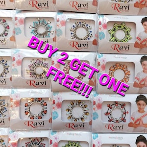 Könnte beinhalten: Eine Auswahl an bunten, mit Schmuck besetzten, selbstklebenden Körperstickern mit dem Text "Ravi Fancy Bindi" und "Making Beauty" auf jeder Karte. Der Text "Buy 2 Get One Free!!" ist über das Bild gelegt.