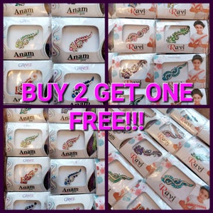 May include: A collage of images showing various packages of colorful temporary body jewelry. The packages are labeled with the brand names "Anam" and "Ravi". The text "BUY 2 GET ONE FREE!!" is superimposed on the image.