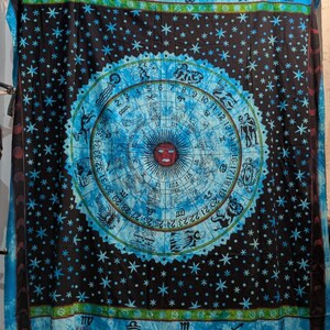 May include: A black and blue tapestry with a celestial design. The center features a zodiac wheel with a red sun. The background is black with blue stars and a blue border. The tapestry is made of a soft material.
