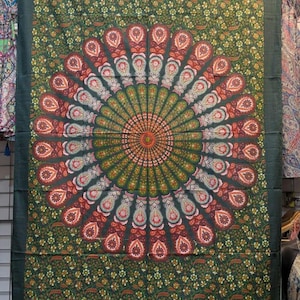 May include: A green tapestry with a central mandala design in shades of orange, red, and green. The mandala is surrounded by a floral pattern. The tapestry has a dark green border.