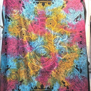 May include: A vibrant tapestry with a central eye design, surrounded by intricate patterns in pink, blue, yellow, and black. The colorful artwork features a psychedelic design, suitable for wall decor or as a bedspread.