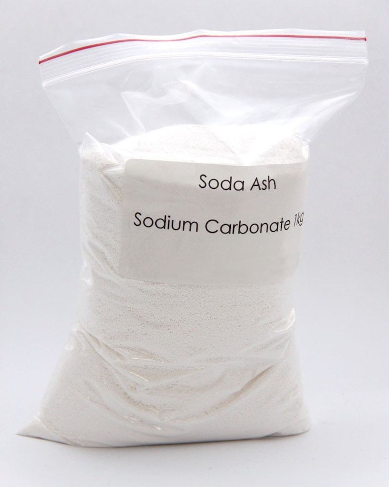 Puede incluir: Una bolsa de pl&aacute;stico blanca llena de polvo blanco con la etiqueta "Soda Ash Sodium Carbonate 1kg".