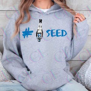 May include: A gray hoodie with a blue hashtag, a football player graphic, and the text "#1 SEED" in blue.
