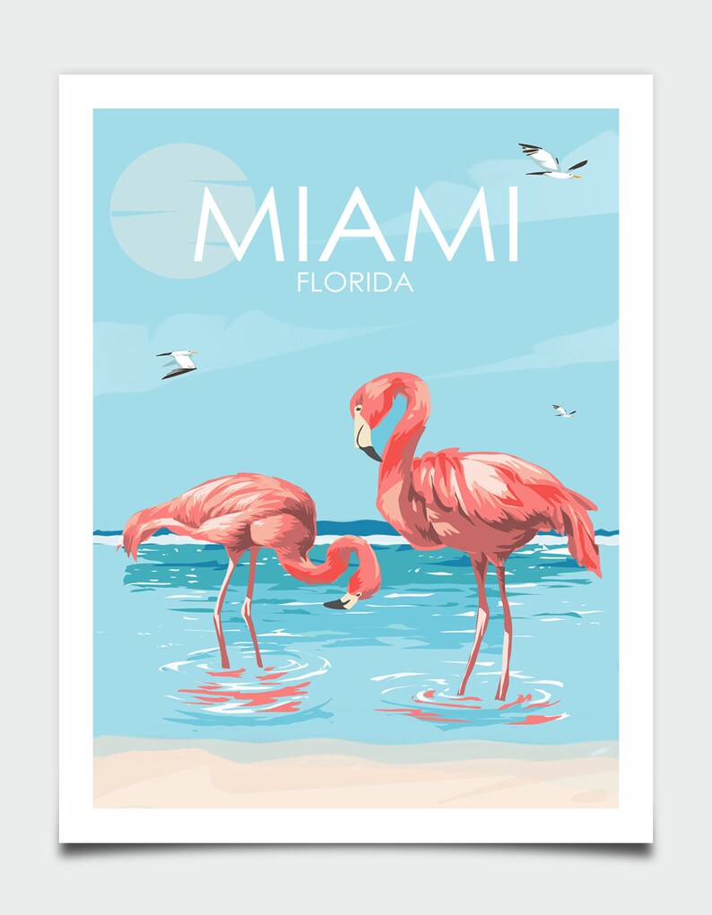 K&ouml;nnte beinhalten: Ein Vintage-Reiseposter mit zwei rosafarbenen Flamingos, die im blauen Wasser stehen, mit einem Sandstrand im Vordergrund. Das Poster hat einen blauen Himmel mit wei&szlig;en Wolken und den Text "MIAMI FLORIDA" oben.