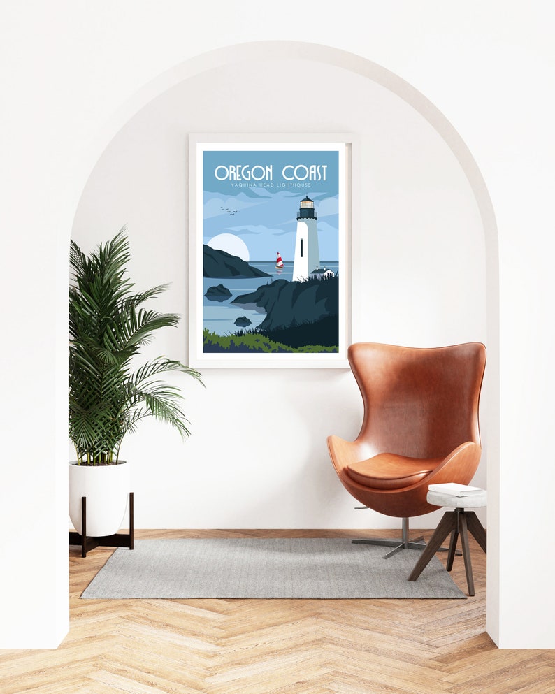 May include: A framed poster with a blue and white illustration of a lighthouse on the Oregon Coast. The poster reads "Oregon Coast, Yaquina Head Lighthouse". The poster is hanging on a white wall in a room with a brown leather armchair and a small wooden side table.