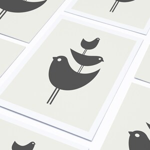 Pu&ograve; includere: Set di tre carte con un design minimalista che presenta silhouette nere di uccelli su uno sfondo grigio chiaro.
