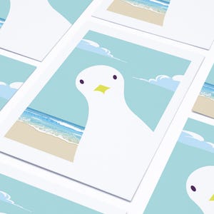 Puede incluir: Un conjunto de tarjetas de felicitaci&oacute;n con una gaviota blanca con un pico amarillo sobre un fondo de cielo azul y oc&eacute;ano. Las tarjetas est&aacute;n en blanco en el interior para escribir mensajes.