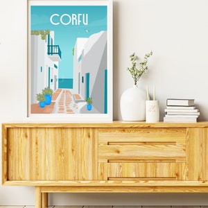 May include: A white framed print with a blue and white illustration of a street in Corfu, Greece. The print is hanging on a white wall above a wooden cabinet.