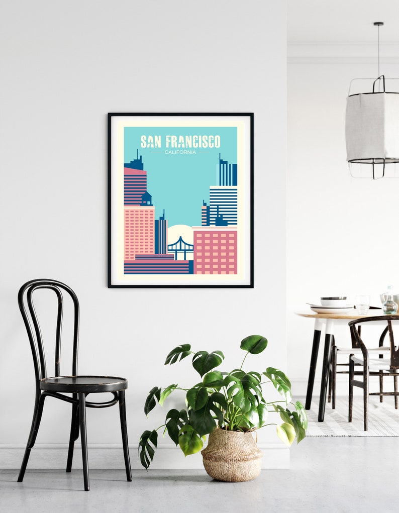 May include: A black framed poster with a graphic design of the San Francisco skyline in pink, blue, and white. The text "SAN FRANCISCO - CALIFORNIA" is at the top of the poster.