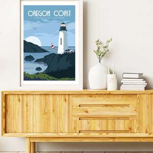 May include: A white framed print with a blue and white illustration of a lighthouse on the Oregon Coast. The text "Oregon Coast" and "Yaquina Head Lighthouse" is printed in blue at the top of the print.