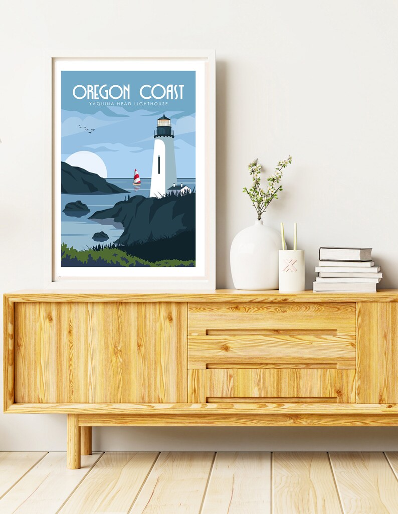 May include: A white framed print with a blue and white illustration of a lighthouse on the Oregon Coast. The text "Oregon Coast" and "Yaquina Head Lighthouse" is printed in blue at the top of the print.