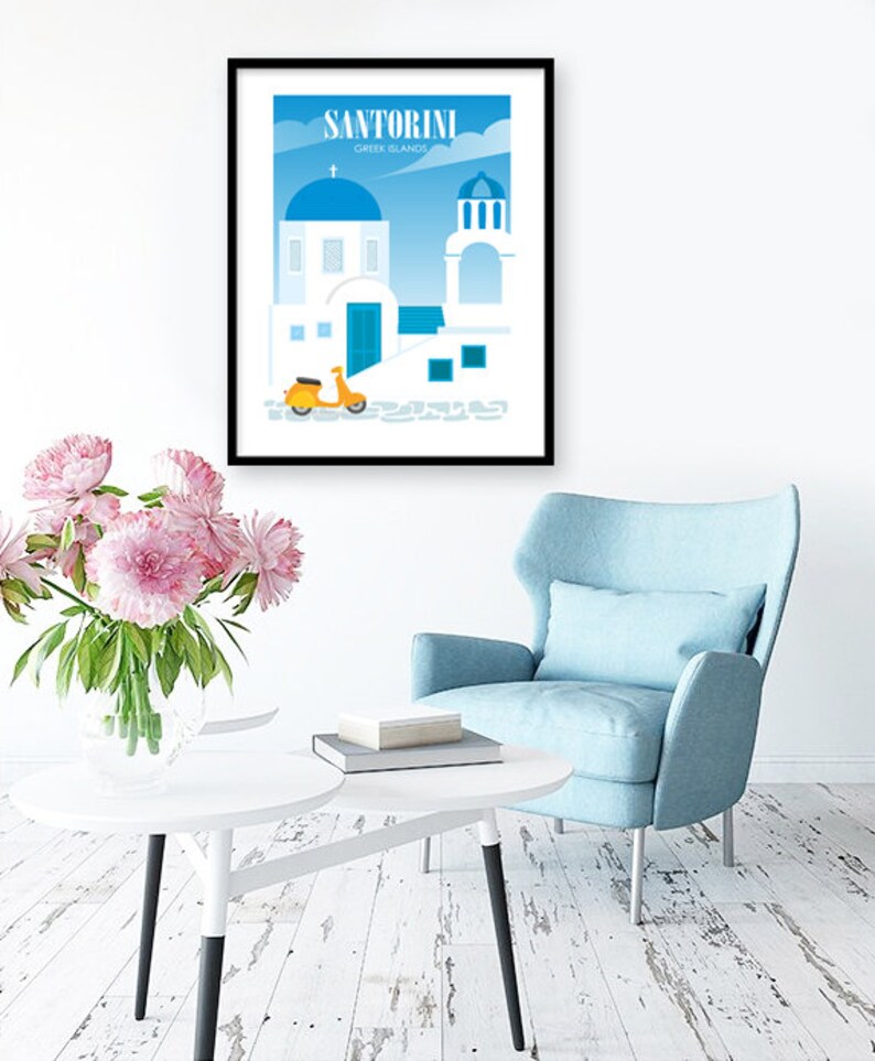 May include: A framed poster with a blue and white illustration of a building in Santorini, Greece. The poster has the text "Santorini Greek Islands" at the top. A yellow scooter is parked in front of the building.