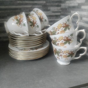May include: A set of vintage teacups and saucers with a floral pattern in shades of brown, yellow, and green. The cups and saucers have a gold trim.