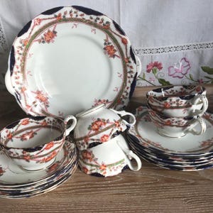 May include: A set of vintage teacups and saucers with a blue and white floral pattern. The cups and saucers are decorated with gold accents and have a delicate, feminine design.
