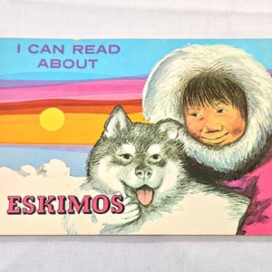 May include: A vintage children's book cover with the text "I CAN READ ABOUT ESKIMOS." The illustration features a smiling person in a fur-lined hood next to a husky dog. The background shows a sunset with a yellow sun and a blue and pink sky.