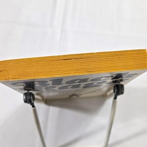 May include: A book titled "Black Rage" with yellowed pages and a black and white cover. The book is propped up on a white metal stand against a white background. The book's edges are a golden yellow color.