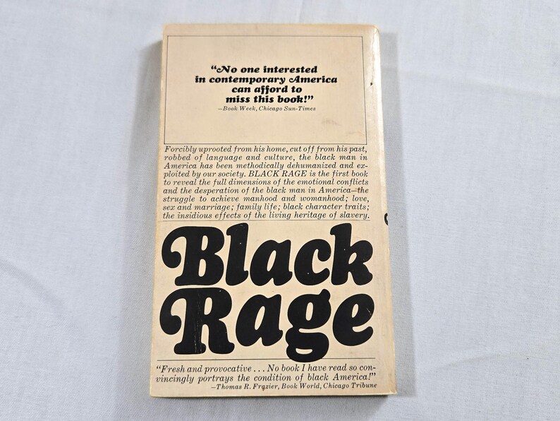 May include: The back cover of the book "Black Rage" is shown. The title is in large, bold, black, stylized letters. The cover has text from book reviews and a description of the book's contents. The background is a light beige color.