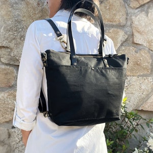 A woman wears the bag on her back with the backpack straps, while the tote handles are not in use.