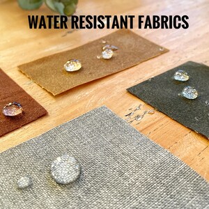 Swatches of waxed canvas and the grey lining fabric. There are drops of water on the swatches to illustrate the waterproof condition of the fabrics.