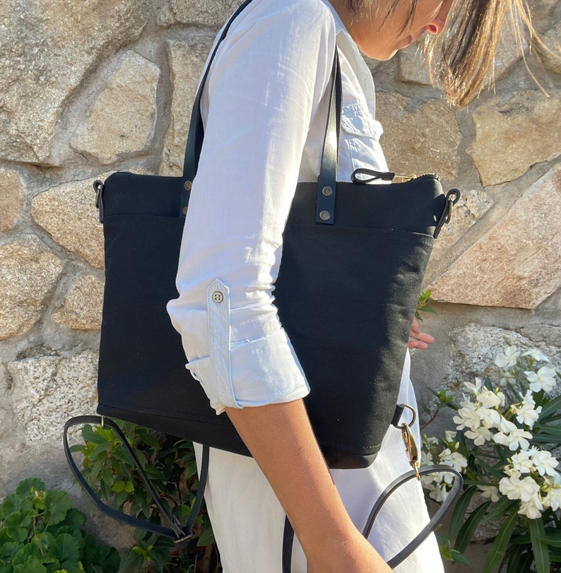 A woman wears the bag as a tote bag with the leather straps on her shoulder.