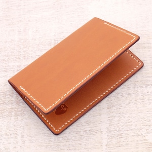 May include: A brown leather card holder with white stitching. The card holder has a small owl logo embossed on the front.