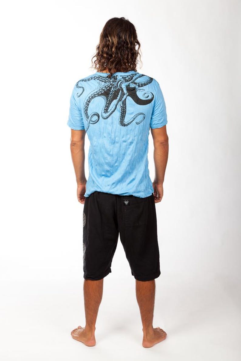 May include: A light blue short-sleeve t-shirt featuring a large black octopus graphic printed across the upper back and shoulders, paired with black knee-length shorts that have a small black label on the back pocket area.