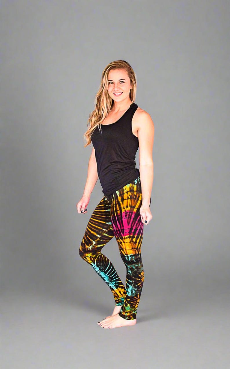 May include: A woman wearing a black tank top and colorful tie-dye leggings. The leggings have a bright yellow, pink, blue, and black pattern.