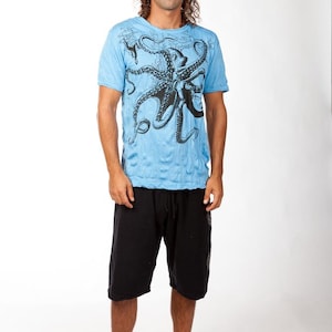 May include: A light blue short-sleeve t-shirt featuring a large black octopus graphic printed on the front, paired with black knee-length shorts that have an elastic waistband and a drawstring closure, creating a casual two-piece outfit.