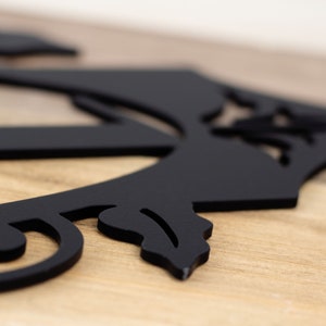 Close up of matte black powder coat on our vertical 3 digit metal house number sign. Placed on a wood plank.